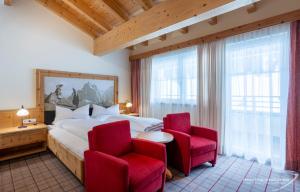 a bedroom with a large bed and two red chairs at Hotel Venter Bergwelt in Vent
