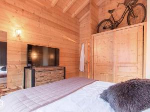 1 dormitorio con 1 cama y TV y una bicicleta en la pared en Chalet Nina, en La Chapelle-dʼAbondance