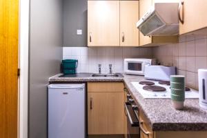 uma cozinha com um frigorífico branco e um lavatório em For Students Only Private Ensuite Rooms with Shared Kitchen at Pittrodrie Street em Aberdeen