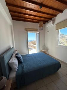 a bedroom with a blue bed and a large window at Agyra House in Super Paradise Beach
