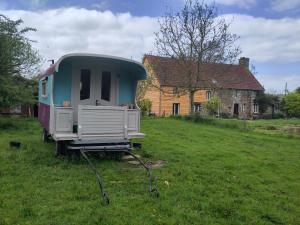 a trailer sitting in a field in front of a house at Chez Marie Roulotte in Pontfarcy