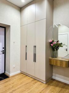 uma cozinha com armários brancos e um vaso de flores em Luxury two-room apartment with beautiful mountain views em Almaty