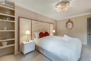 Un dormitorio con una gran cama blanca y una lámpara de araña. en The Shepherd Residence en Londres