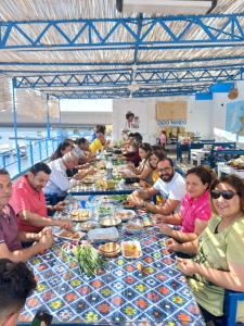 Un groupe de personnes assises autour d'une longue table avec de la nourriture dans l'établissement Endo Mando, à Shellal