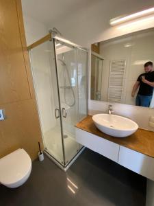 un hombre tomando una foto de un baño con lavabo y ducha en Wileńska Residence, en Varsovia