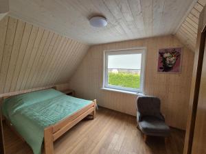 a bedroom with a bed and a window and a chair at Namas Zarasuose su vyno rūsiu in Zarasai