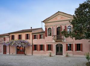 un edificio rosa con un árbol florido delante de él en La tua villa, en Motta di Livenza