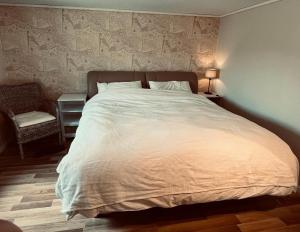 1 dormitorio con 1 cama blanca grande y 1 silla en The Fisher's cabin en Stjoerdal