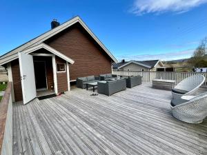 una terraza de madera con sillas y mesas en una casa en The Fisher's cabin en Stjoerdal