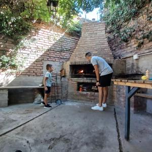 Um homem e um rapaz em frente a um forno de tijolos. em Mendoza - Casa Cardozo em Guaymallén
