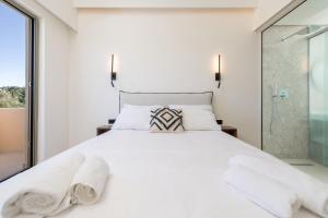 1 dormitorio con cama blanca y ducha acristalada en Little Corfu, en Dassia