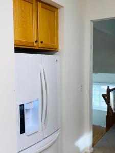 einen weißen Kühlschrank in einer Küche mit Holzschränken in der Unterkunft National Habor Luxury room in Fort Washington