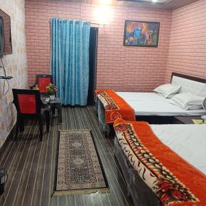 a room with two beds and a table with a chair at Somnath dham in Vrindāvan