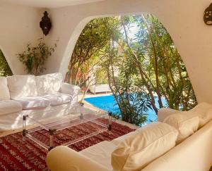 ein Wohnzimmer mit weißen Sofas und einem Glastisch in der Unterkunft Villa Hirondelles 35 in Cavalaire-sur-Mer