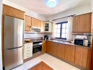 a kitchen with wooden cabinets and a stainless steel refrigerator at Casa Inma Las Piteras. Sol y agua in Costa Teguise