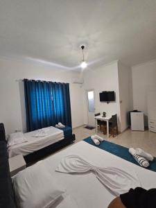 a hotel room with two beds and a television at DEA Room 2 in Sarandë +6 photos