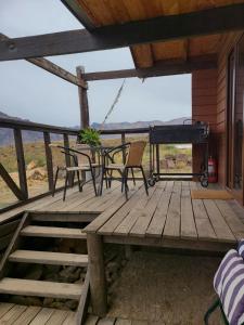 a wooden deck with chairs and a piano at Tierras Bayas Mountain Refuge in Los Cipreses