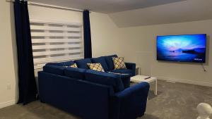 ein Wohnzimmer mit einem blauen Sofa und einem Flachbild-TV in der Unterkunft Welcome to Bethel in Carrying Place