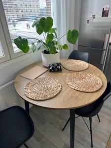 una mesa de madera con dos platos y una maceta en ella en Stunning city center studio with balcony 37 m2, en Lappeenranta