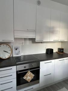 a kitchen with white cabinets and a clock and an oven at Stunning city center studio with balcony 37 m2 in Lappeenranta