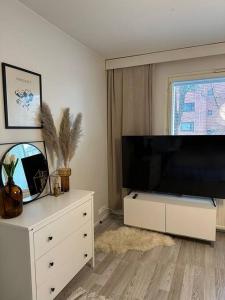 a living room with a large television and a white dresser at Stunning city center studio with balcony 37 m2 in Lappeenranta