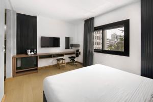 尼科西亞的住宿－Urban Habitat Executive Suites，一间卧室配有一张床、一张书桌和一台电视