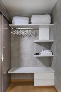 a closet with white shelves and white towels at Urban Habitat Executive Suites in Nicosia