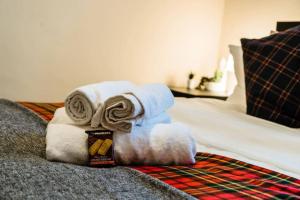 una pila de toallas sentadas encima de una cama en Caledonia Suite - Netflix Free Parking en Glasgow