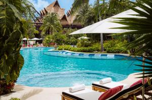 a pool at a resort with chairs and an umbrella at Vidanta Riviera Maya in Puerto Morelos