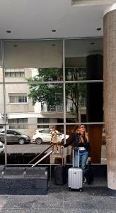 une femme assise avec ses bagages devant un bâtiment dans l'établissement Recoleta Loft con Terrazas, à Buenos Aires