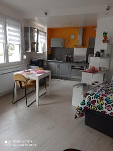 a kitchen with a white table and a bed at L'arc-en-ciel in Le Tréport