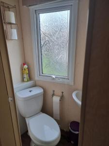 a bathroom with a toilet and a window at Summerlands, Ingoldmells 8 berth caravan in Skegness