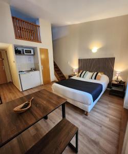 Cette chambre comprend un grand lit et une table. dans l'établissement Hôtel Le Valois, Cognac Centre, à Cognac