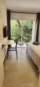 Cette chambre comprend un lit, une chaise et une fenêtre. dans l'établissement Flat Moderno Pé na Areia no Cumbuco Piscina e Localização Perfeitas Eco Paradise, à Caucaia