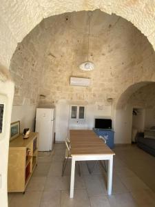 un soggiorno con un tavolo e un muro di pietra di Affittasi Trullo il Gelso - Ostuni a Carovigno