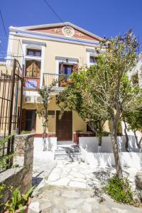 una casa con un árbol delante de ella en Symi Center Hotel en Symi