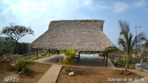 een hut met een rieten dak en palmbomen bij Rancho Agua Fria in Jucuarán