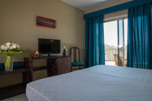 1 dormitorio con cama, TV y balcón en Hotel Aeropuerto Sur, en San Isidro