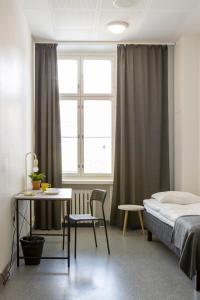 a bedroom with a bed and a table and a desk at Hostel Bjorkenheim in Seinäjoki