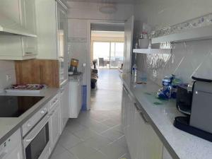 una cocina con armarios blancos y una barra larga en Magnifique 3P front de mer, en Juan-les-Pins