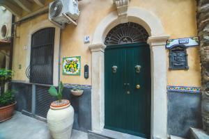 a green door on a building with a vase in front at 4Roomsrelax in Catania