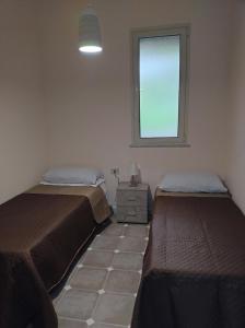 a bedroom with two beds and a window at Home SG jato in San Giuseppe Iato