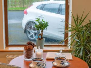 una mesa con tazas y macetas y un coche en una ventana en The Gardens B&B en Birr