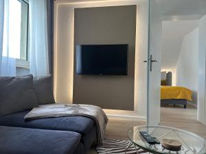 - un salon avec un canapé et une télévision murale dans l'établissement Apartment- La Mia, à Castrop-Rauxel