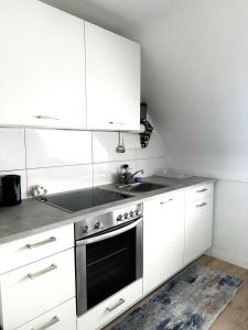 La cuisine est équipée de placards blancs, d'un évier et d'une cuisinière. dans l'établissement Apartment- La Mia, à Castrop-Rauxel
