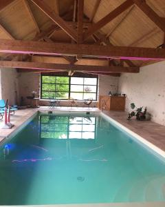 uma grande piscina num grande quarto com uma grande janela em MAISON DE VACANCES AVEC PISCINE INTERIEURE - Le Grand Champagne em Saint-Victeur