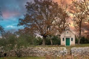 uma pequena capela num campo com uma parede de pedra em The Nook em Bilice