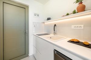 a white kitchen with a sink and a counter at Levanda apart in Dassia
