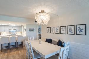 a dining room with a white table and a chandelier at Luxury, Direct Oceanfront Unit and Balcony, Northeast Corner, Heated Pool, Garage Parking in Ormond Beach