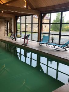 ein Haus mit einem Pool mit Stühlen und Wasser in der Unterkunft MAISON DE VACANCES AVEC PISCINE INTERIEURE - Le Grand Champagne in Saint-Victeur